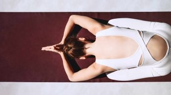 Young woman practicing yoga on yoga mat indoors. Girl meditating and doing relaxing yoga poses at home. Female training for health body and mind. Concept of no stress, female happiness and zen energy